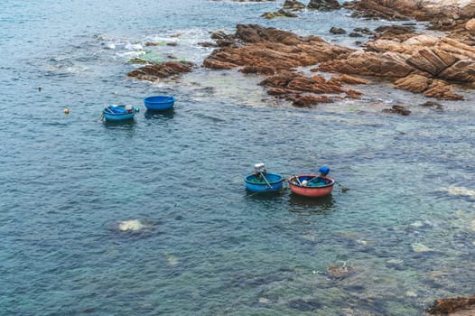 Vietnamese round basket boats floating in sea next to the rocks
