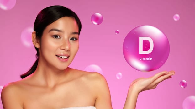 A young woman presents a graphic bubble promoting vitamin D benefits. She is smiling and enjoying the moment, exuding confidence in a vibrant pink setting.