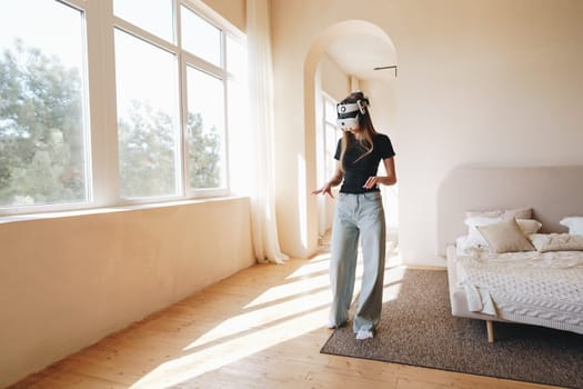 A person explores a virtual reality environment while wearing a headset in a spacious and sunlit room. The modern interior features light-colored walls and simple furniture.