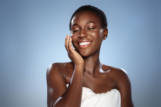 A woman expresses happiness while gently touching her face, emphasizing her radiant skin. The bright background enhances her joyful demeanor, highlighting beauty and self-care.