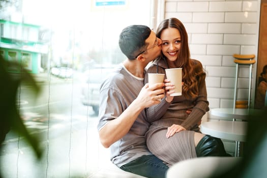 Two people share a joyful moment at a cafe, smiling and sipping from cups. The urban setting is bright, creating a warm and inviting atmosphere for their connection.