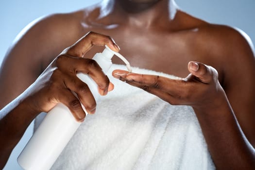 A woman is seen dispensing lotion into her hand while wrapped in a towel. She is in a softly lit bathroom reflecting a calming morning atmosphere dedicated to self-care.