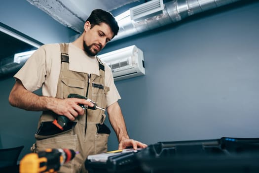 A man in work overalls inspects tools and plans before starting a project in a contemporary environment. His focused demeanor shows dedication to his craft.