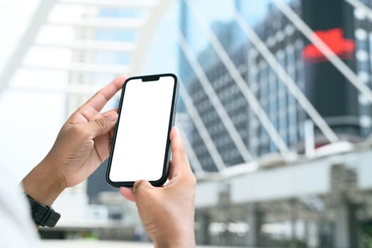 Man using a smartphone with empty screen in front of modern city.