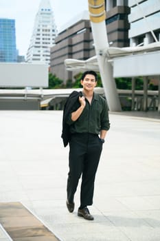 Handsome businessman walking confidently through a modern cityscape.