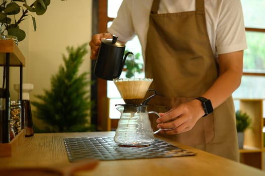Man pouring hot water into a coffee dripper, enjoying a mindful morning routine.