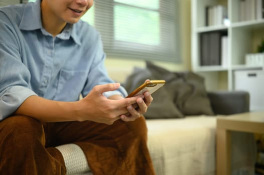 Close up of young man using smartphone sitting on a sofa.