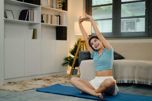 Attractive young woman stretching on mat during a home workout.