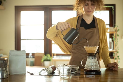 Calm young woman making a fresh cup of coffee using pour-over method.