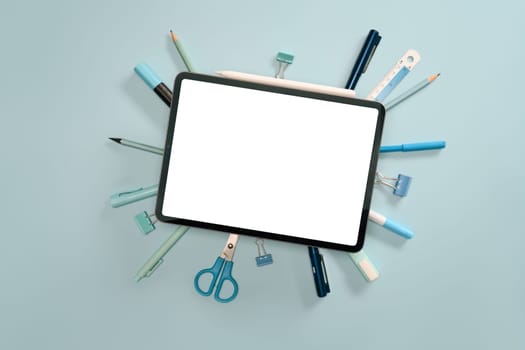 Top view of school or office supplies arranged around digital tablet. Education, or remote work visuals concept.