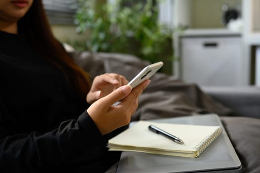 Close up of woman hands using smartphone on sofa at home.