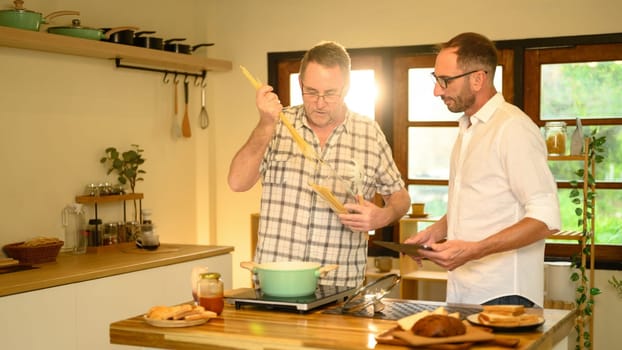 Happy father and son preparing a meal together and conversation in a kitchen. Fathers day concept.