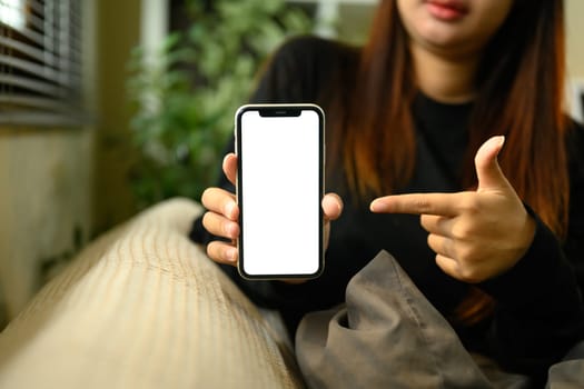 Woman pointing at smartphone with blank display ready for digital content showcase.