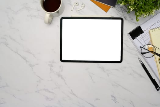 Top view of digital tablet with blank screen on a white marble desk.