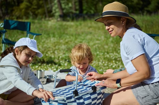 A joyful family picnic featuring a mother and her children, enjoying outdoor activities in a sunny natural setting, fostering strong family bonds and creating happy summer memories.