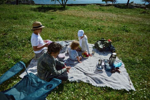 A family enjoys a refreshing picnic in the mountain wilderness. Surrounded by nature, they share moments of happiness and connection under the sun.