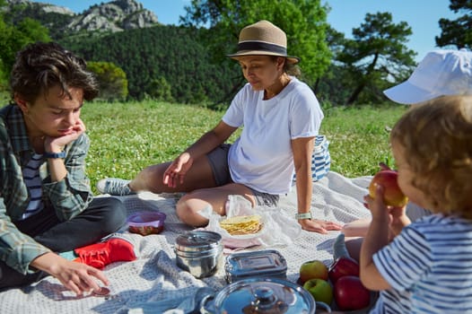 A family gathers for a peaceful outdoor picnic in a picturesque mountain setting. Warm summer weather, delicious food, and bonding moments in the beauty of nature create lasting memories.