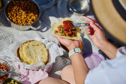 A family enjoying a picnic in nature, preparing tacos with fresh ingredients, celebrating togetherness and enjoying the outdoors during a bright summer day.