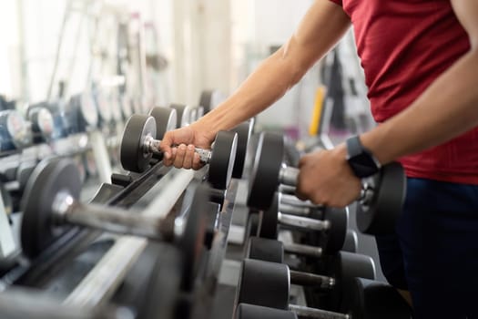 A person performs strength training with dumbbells, focusing on wellness and fitness in a modern gym setting.