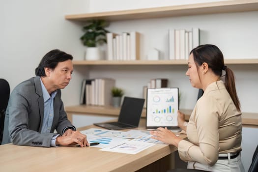 Two colleagues engage in a business meeting, analyzing financial reports and discussing strategies in a contemporary office.