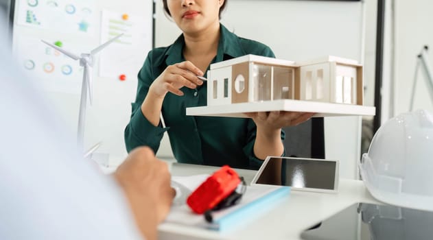 A dedicated professional presents a sustainable building model, highlighting innovative design and ESG commitment.