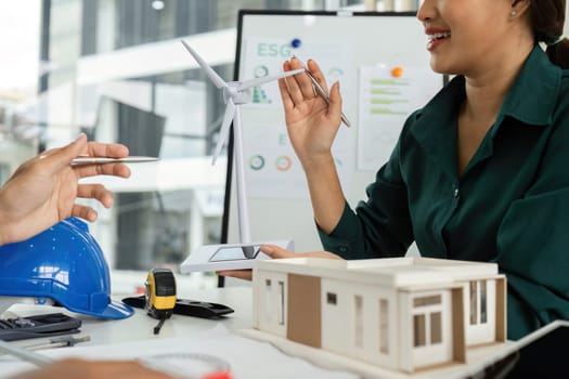 A diverse team collaborates on sustainable building designs, focusing on renewable energy and environmental impact.
