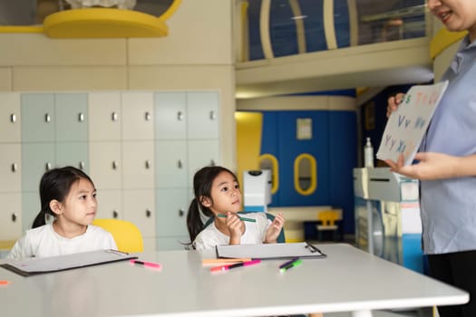 A teacher enthusiastically guides two young girls during a back-to-school session, fostering a fun learning environment.