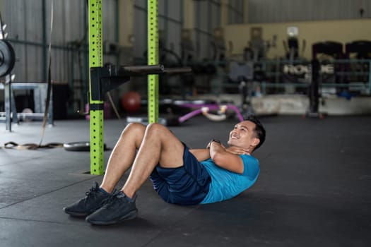A man performs crunches in a gym, focusing on core strength and fitness as part of his workout routine.