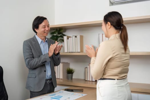 Two business professionals celebrate their success with applause in a contemporary office, highlighting teamwork and achievement.