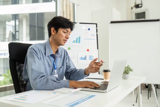 A young professional analyzes business data on a laptop, showcasing the digital transformation in a modern office setup.