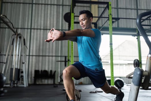 A young man executes a lunge exercise in a gym, emphasizing strength and fitness training for overall health.