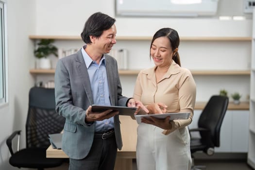 A businessman and businesswoman engage in a friendly discussion while reviewing documents, showcasing teamwork and collaboration.