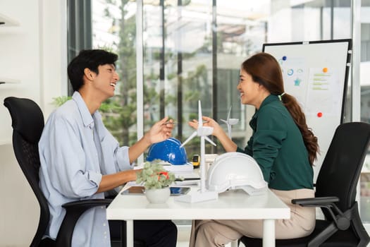 A man and woman engage in a productive discussion about ESG initiatives and sustainable projects, showcasing models and ideas in a modern office.