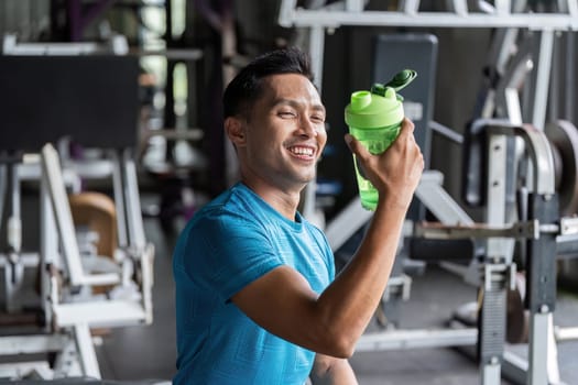 A man joyfully holding a shaker bottle after a workout, celebrating fitness achievements. The atmosphere is vibrant and uplifting.