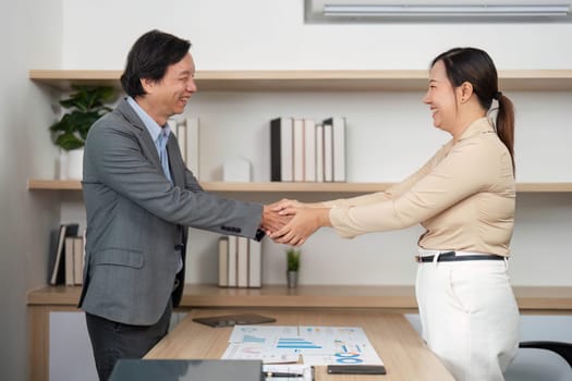 Two business professionals engaging in a handshake, symbolizing partnership and collaboration in a contemporary office setting.
