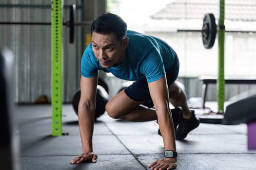 A man performs mountain climbers in a gym, demonstrating a high-intensity cardio workout for fitness enthusiasts.