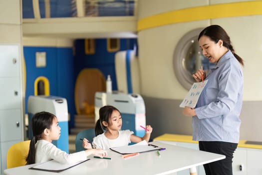 A teacher showcases the alphabet to curious students in a vibrant classroom, fostering a love for learning through interaction.