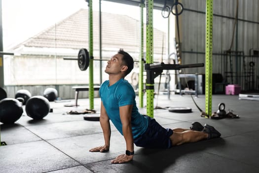 A fit man engaging in yoga stretches in a modern gym, promoting flexibility and wellness. Ideal for fitness and health themes.