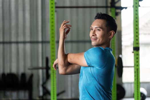 A man engages in an arm stretch in a gym, showcasing the importance of flexibility in fitness routines.