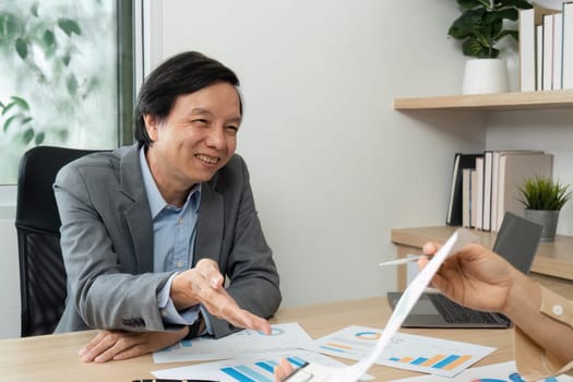 Positive business meeting atmosphere as professionals engage in a handshake, discussing financial strategies and reports.