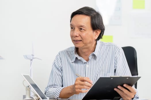 A senior businessman reviewing important ESG documents in a modern office setting, focusing on sustainable business practices.
