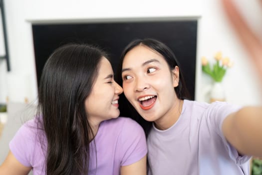 Two young women lean in close, smiling brightly as they take a selfie, showcasing their playful relationship and connection.