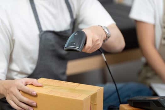 A couple efficiently scans packages with a barcode scanner, showcasing teamwork in a logistics setting focused on productivity.