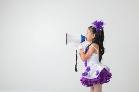 Cheerleader girl in a purple and white outfit using a megaphone. Studio shot on white background, showcasing her energetic, festive, and spirited vibe. A fun portrait of a young cheerleader.