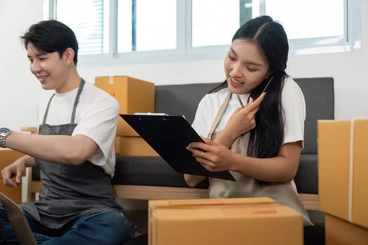 A couple engaged in their e-commerce tasks, with one on the phone and the other organizing packages in a home office.