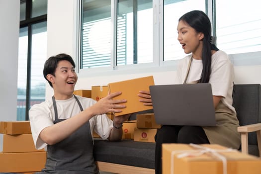 A couple shares a joyful moment while exchanging packages, highlighting their teamwork and positive interaction in a modern office.