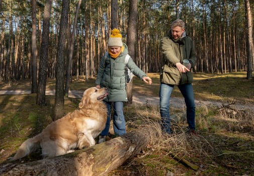 Dad And Daughter Walking In The Forest With A Golden Retriever In Spring