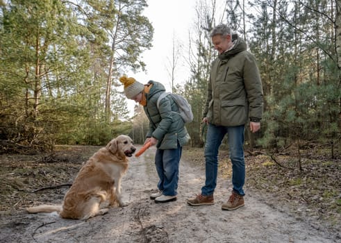 Dad And Daughter Walking In The Forest With A Golden Retriever In Spring