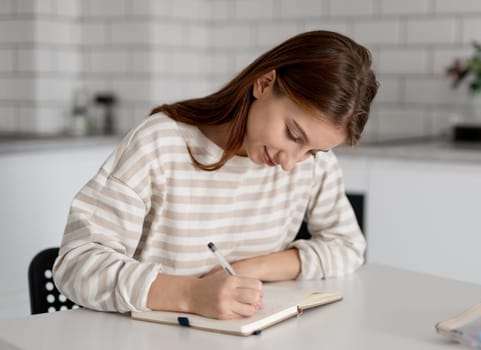 Happy Girl Doing Homework At Home At The Table