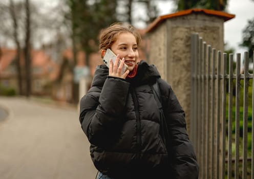 Happy Girl Talking On The Phone Against A Blurred Street Background